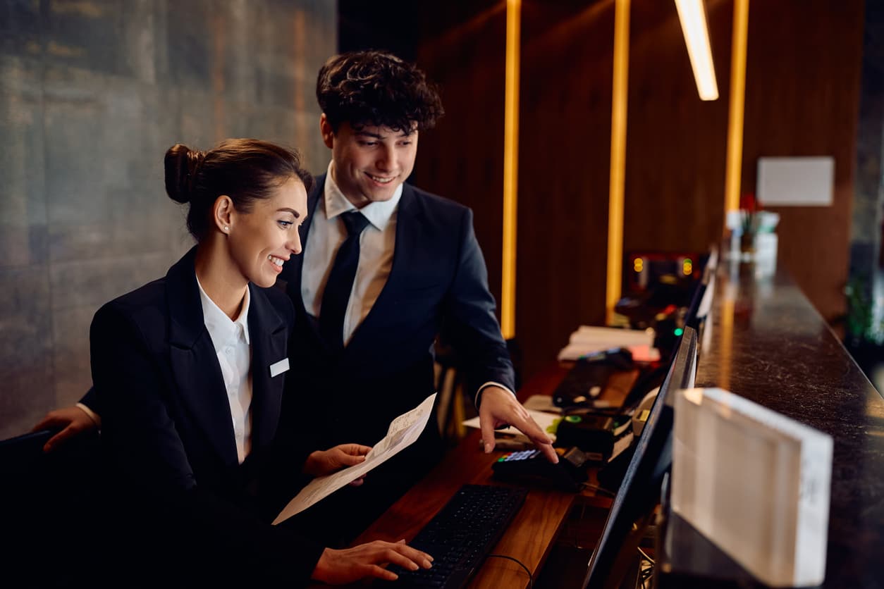 Deux réceptionnistes consultant l'écran du poste d'accueil d'un hôtel